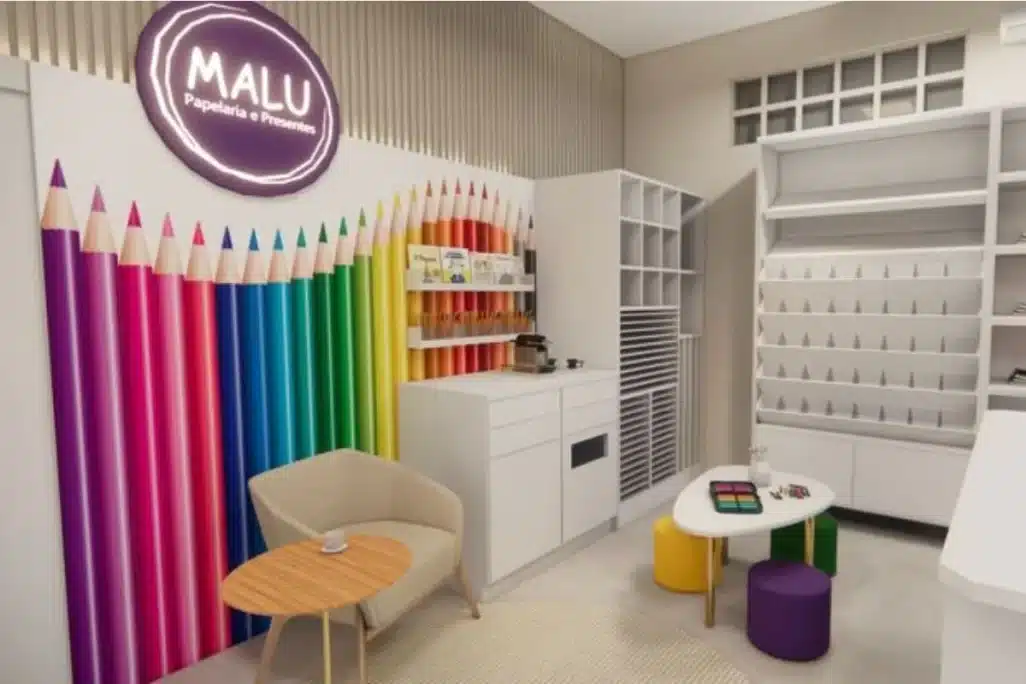 Projeto de reforma da Malu Papelaria com parede colorida em forma de lápis e mobiliário funcional
