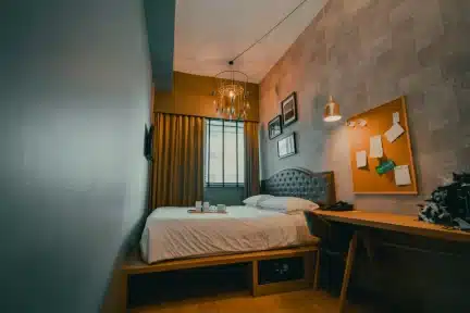 Interior de kitnet moderna com cama, escrivaninha e decoração em tons terrosos - exemplo de quanto custa construir kitnet